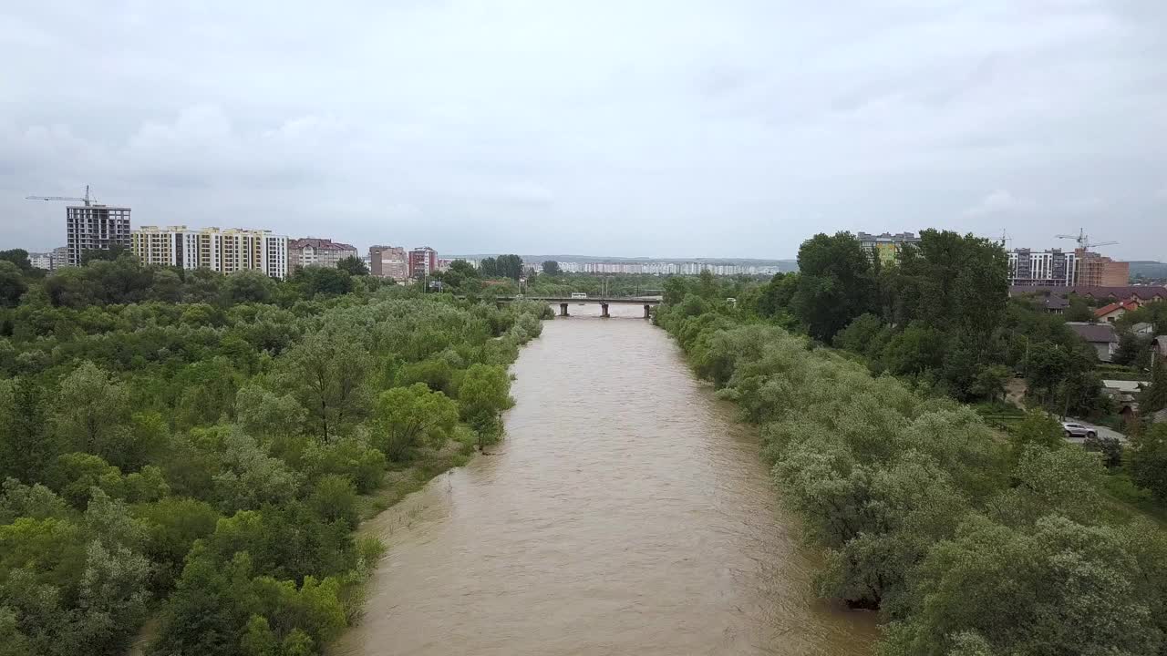 鸟瞰图宽阔的肮脏的河流与浑浊的黄色的水流经一个城市在洪水期间在春季大雨。视频素材