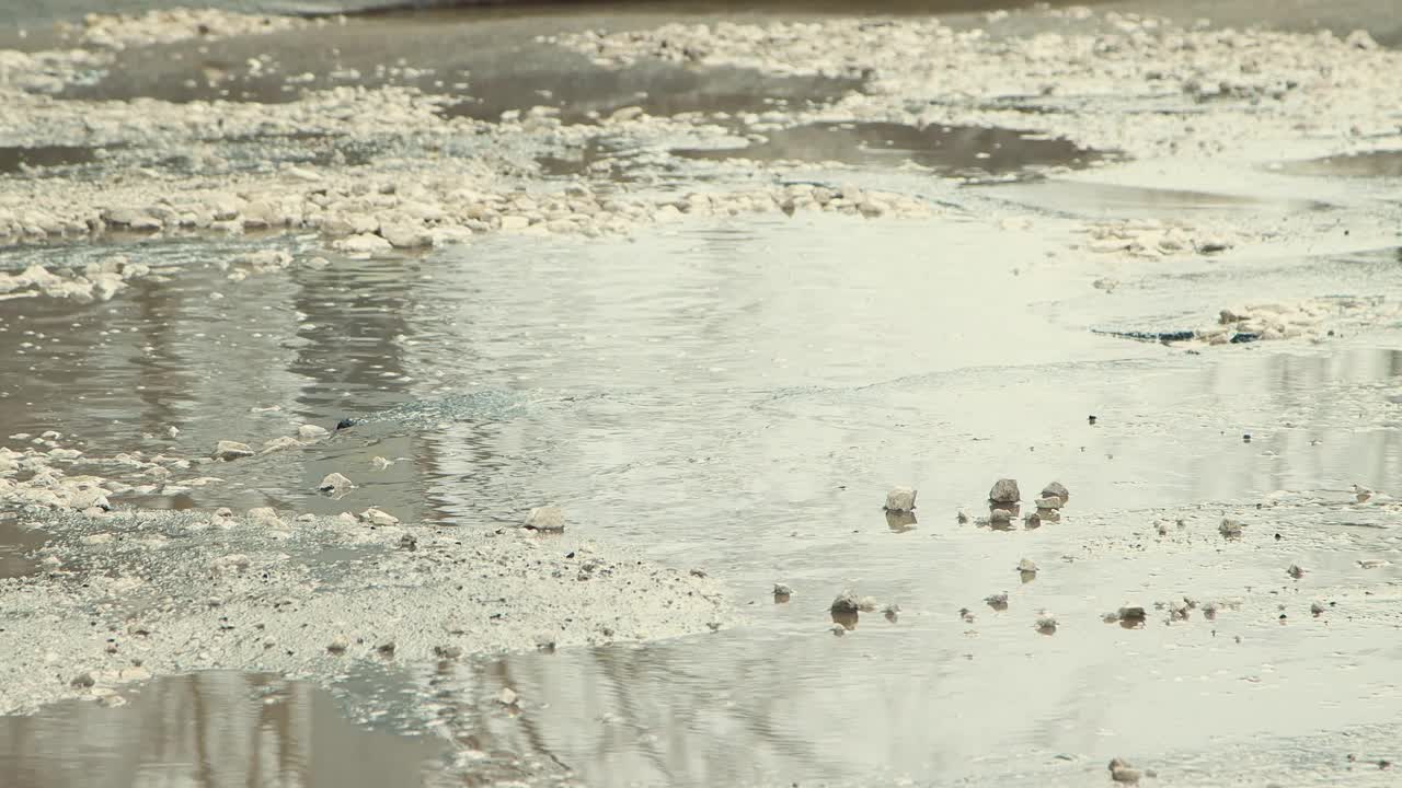 雨后坑洞被水淹没，道路基础设施遭到严重破坏。视频素材