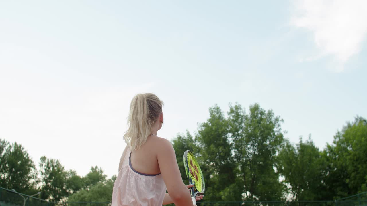 网球选手在室外红土场上用力击球给对手的后视图。不知名的女运动员训练技巧练习专业运动慢动作。医疗保健视频素材