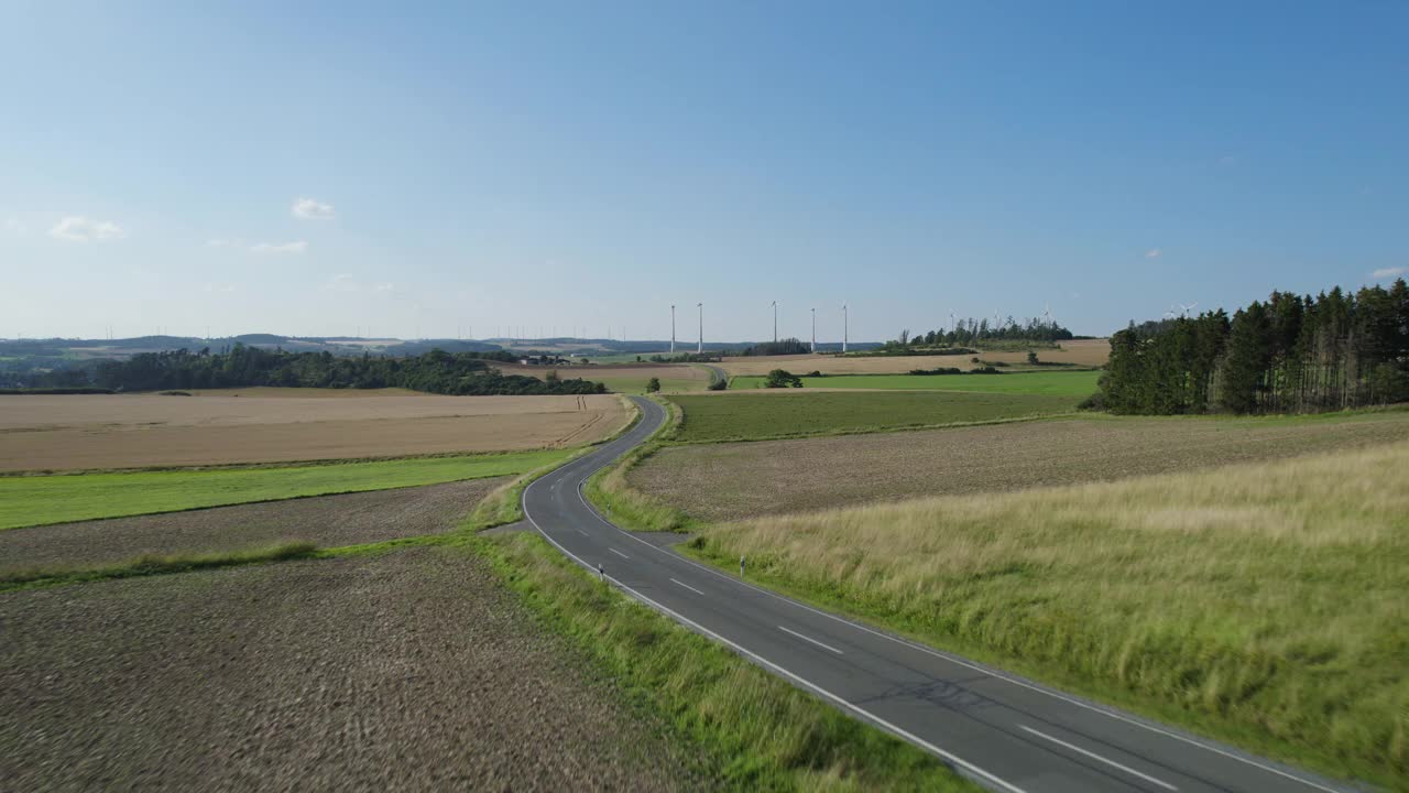 乡村风景中的乡村道路，地平线上有风力涡轮机(空中)视频素材