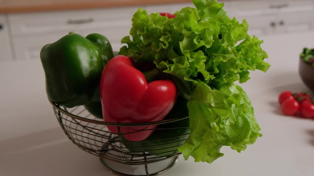 新鲜的蔬菜沙拉，红绿辣椒和圣女果放在桌子上，背景是白色的厨房视频素材