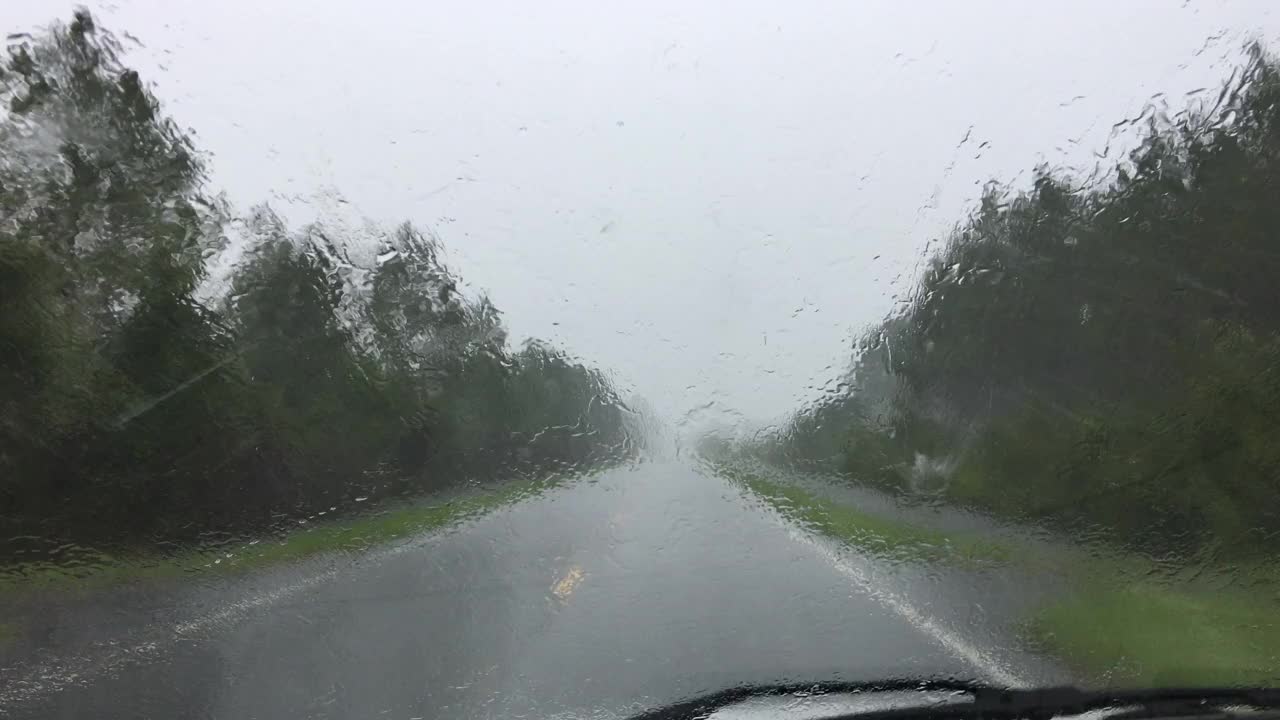 乡村森林道路上的司机视野，雨刷无法清除眩目的雨视频素材