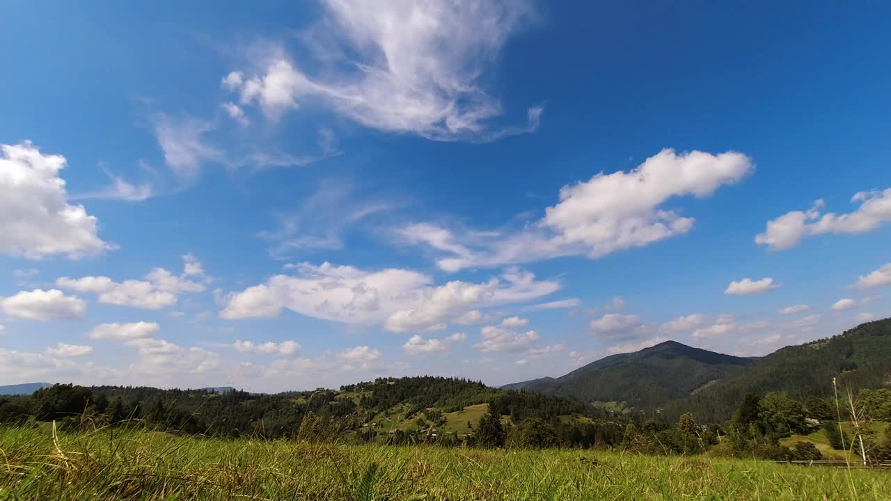 时间流逝:在阳光明媚的日子里，美丽的云朵漂浮在山上的天空中。视频素材