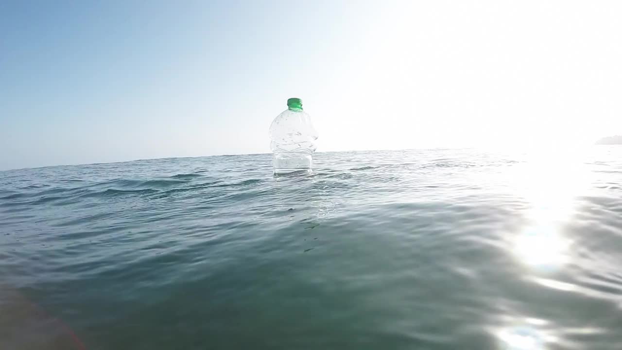 塑料瓶里有泥土，漂浮在海里视频素材