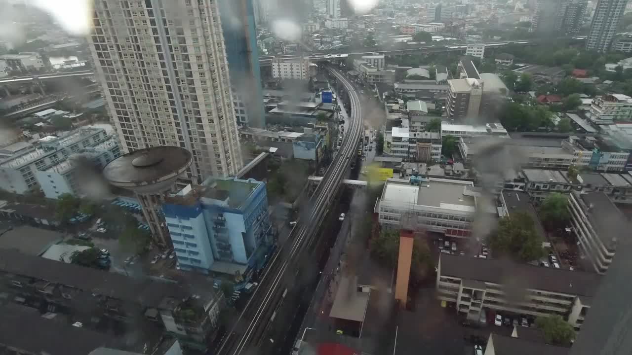 雨点落在窗户上。鸟瞰图。在泰国曼谷的雨季，起居室窗外下着雨。窗外是模糊的雨，城市建筑，道路和天空。视频素材