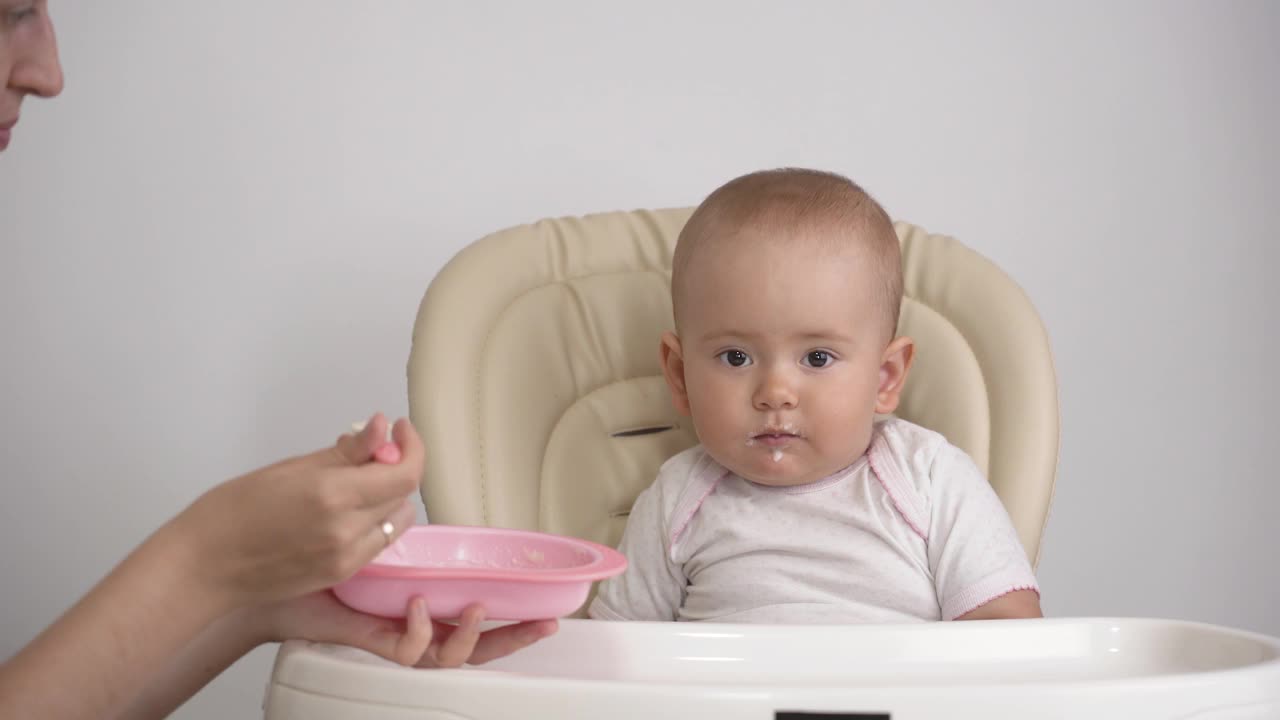 妈妈用汤匙喂婴儿。母亲用勺子盛粥，然后喂婴儿视频素材