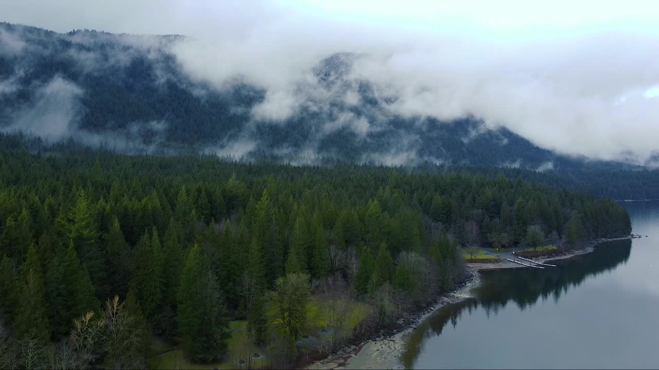 湖上的海滩和周围的山脉和森林的开场镜头视频素材