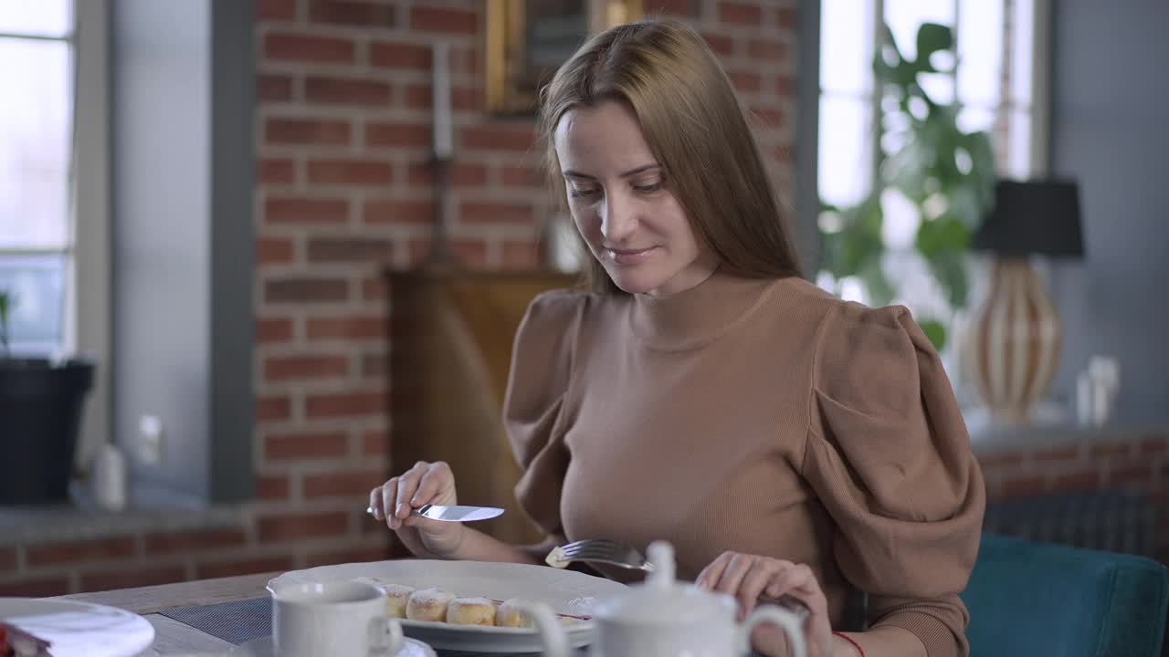 满意的年轻白人女性在餐厅微笑着品尝甜美美味的甜点。快乐美丽自信的女士在室内慢动作用餐。视频素材