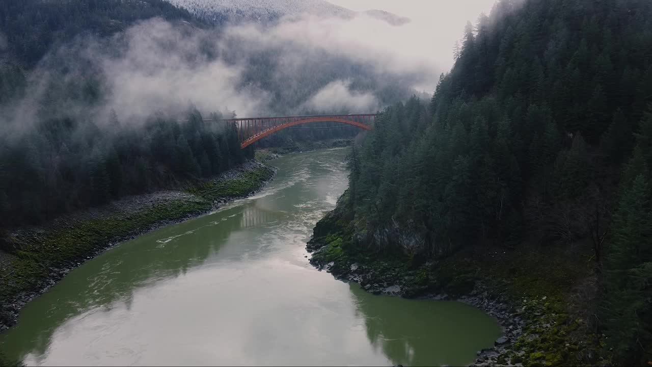 飞向大桥的白色汽车经过，上面的河被群山包围视频素材