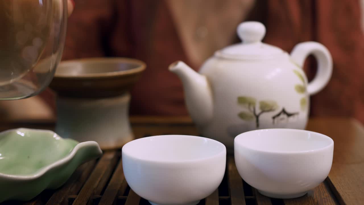 在茶区有一个冲泡和品尝中国绿茶的仪式。把玻璃茶壶里的茶倒进小茶杯里视频素材