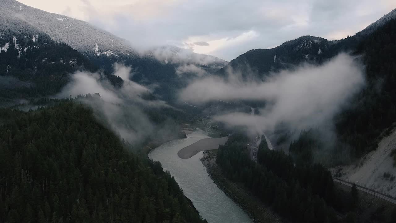 山谷在云中与快速流动的河流和周围的绿色森林覆盖着晨云视频素材