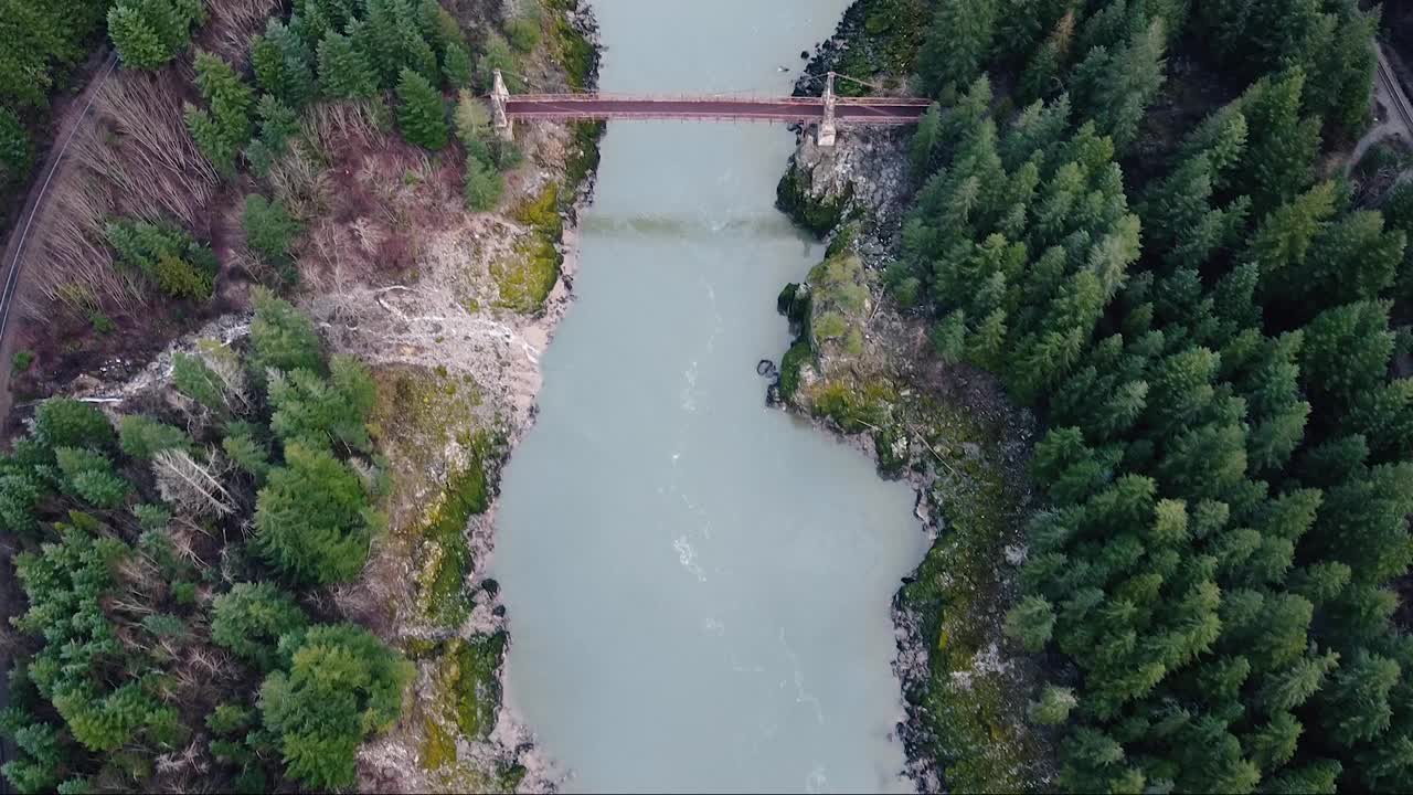 飞过一座古老的桥，桥上的河流环绕着绿色的松林视频素材