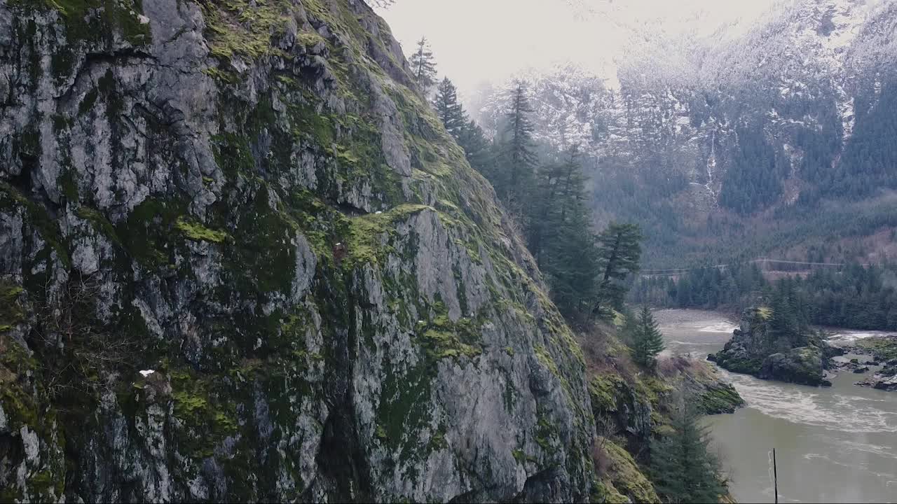 加拿大落基山脉附近的近距离飞行拍摄，河流在后面，山脉被雪覆盖视频素材