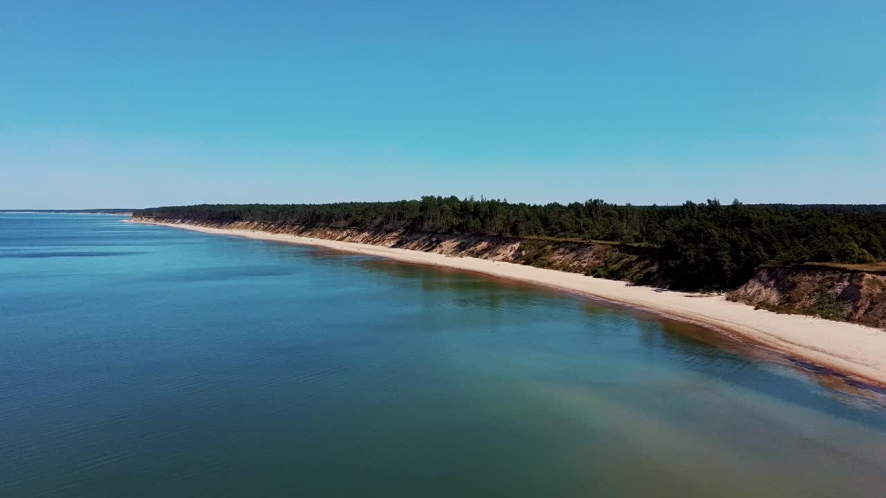 飞越海岸线波罗的海Jurkalne海滨悬崖附近的Pavilosta拉脱维亚和山体滑坡与杂草丛生，波纹洞点缀悬崖和鹅卵石。空中Dron视图。视频素材