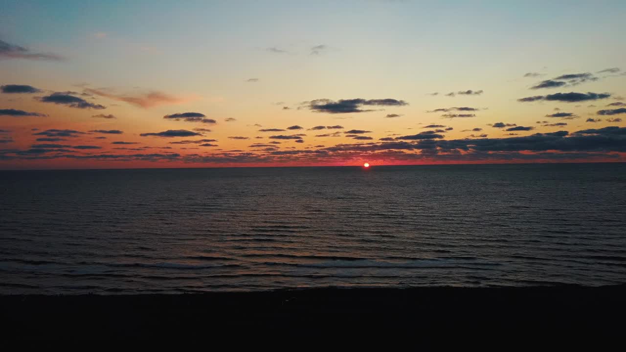 德龙在美丽的日落中飞越大海。空中无人机拍摄。海上的日出。拉脱维亚，波罗的海的彩色日落。视频素材