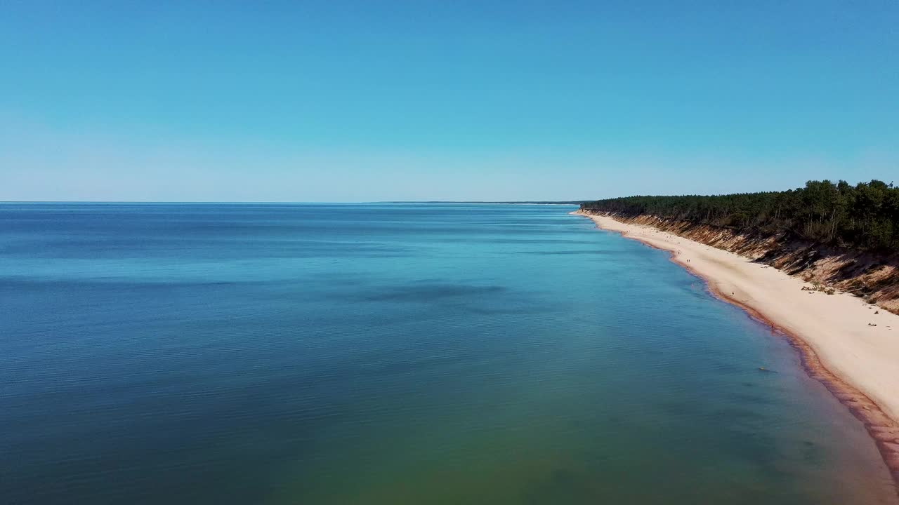 飞越海岸线波罗的海Jurkalne海滨悬崖附近的Pavilosta拉脱维亚和山体滑坡与杂草丛生，波纹洞点缀悬崖和鹅卵石。空中Dron视图。阳光明媚的夏天视频素材