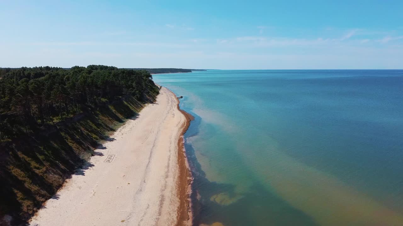 飞越海岸线波罗的海Jurkalne海滨悬崖附近的Pavilosta拉脱维亚和山体滑坡与杂草丛生，波纹洞点缀悬崖和鹅卵石。空中Dron视图。阳光明媚的夏天视频素材