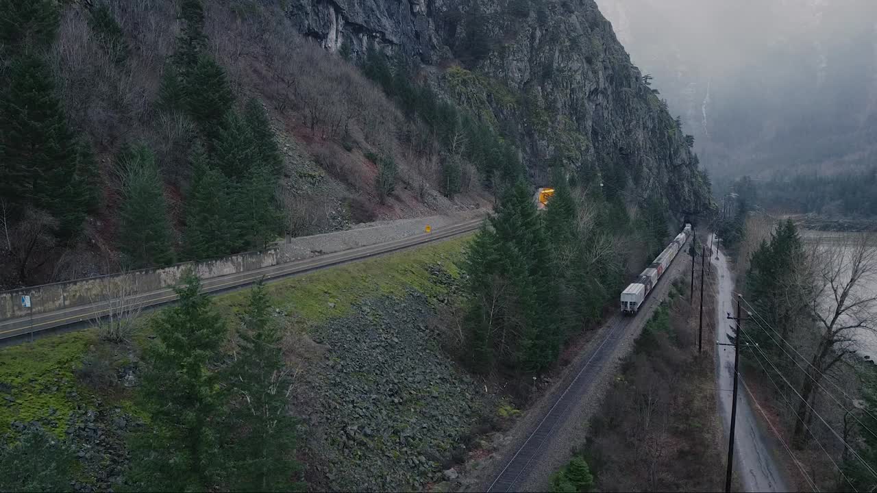 火车正驶向山上的隧道，小路也通向隧道，旁边有一条湍急的河流视频素材