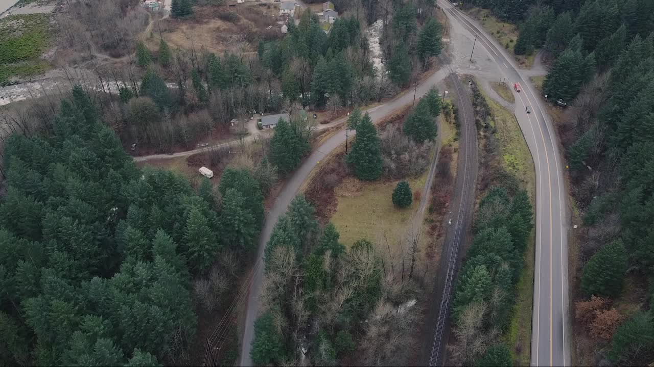 鸟瞰加拿大公路上的两辆孤独的汽车和一列火车从树后驶过视频素材