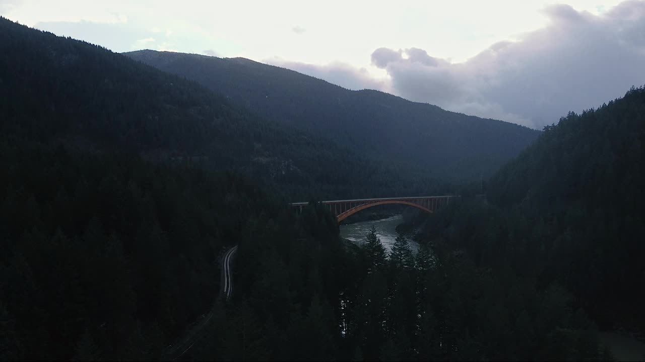 鸟瞰桥上的河流和覆盖着绿色森林的山脉视频素材