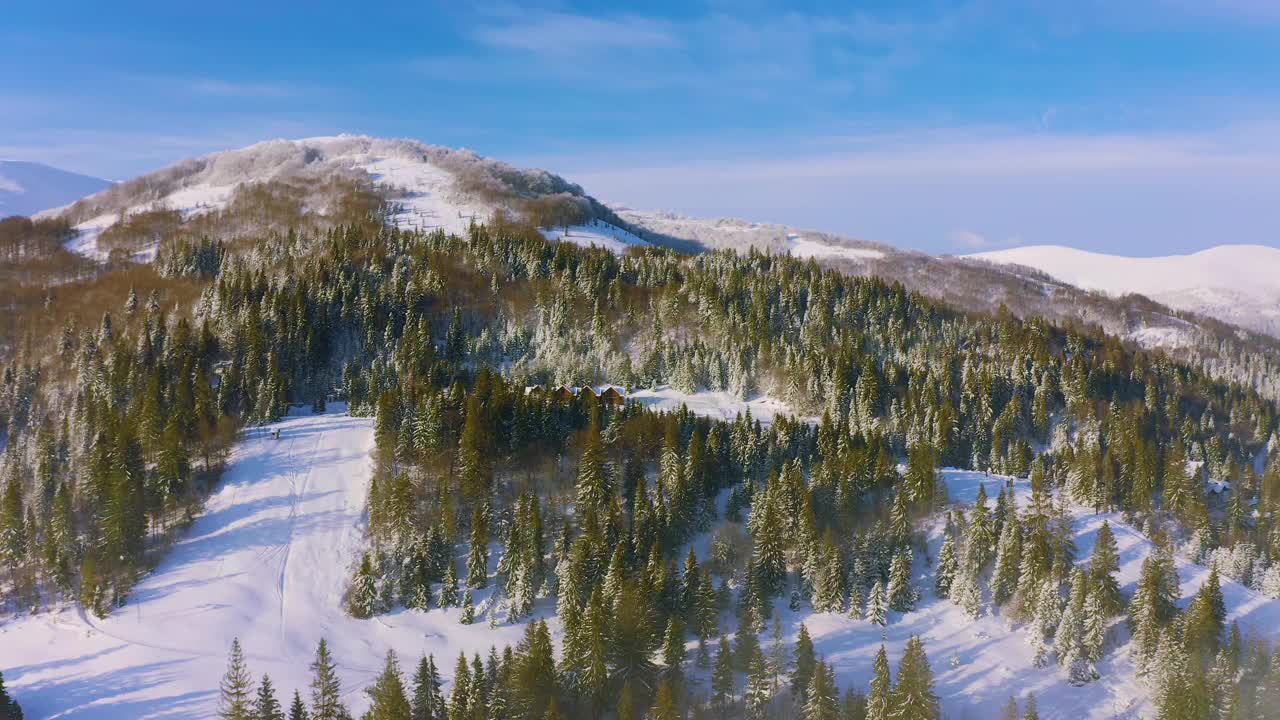 雾蒙蒙的山谷覆盖着白雪覆盖的山脉和绿色的森林视频素材