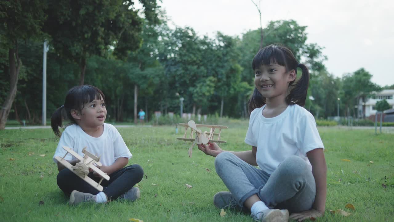 两个亚洲女孩在模型飞机上玩得很开心。视频素材