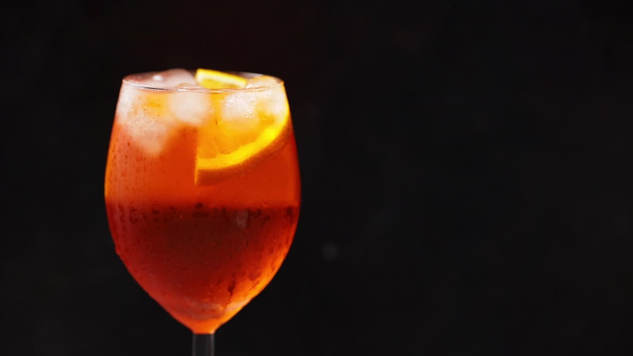 鸡尾酒aperol喷雾器在黑色背景上旋转。夏日橙子鸡尾酒旋转杯。旋转。本空间视频素材