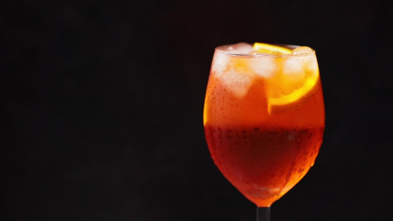 鸡尾酒aperol喷雾器在黑色背景上旋转。夏日橙子鸡尾酒旋转杯。旋转。本空间视频素材