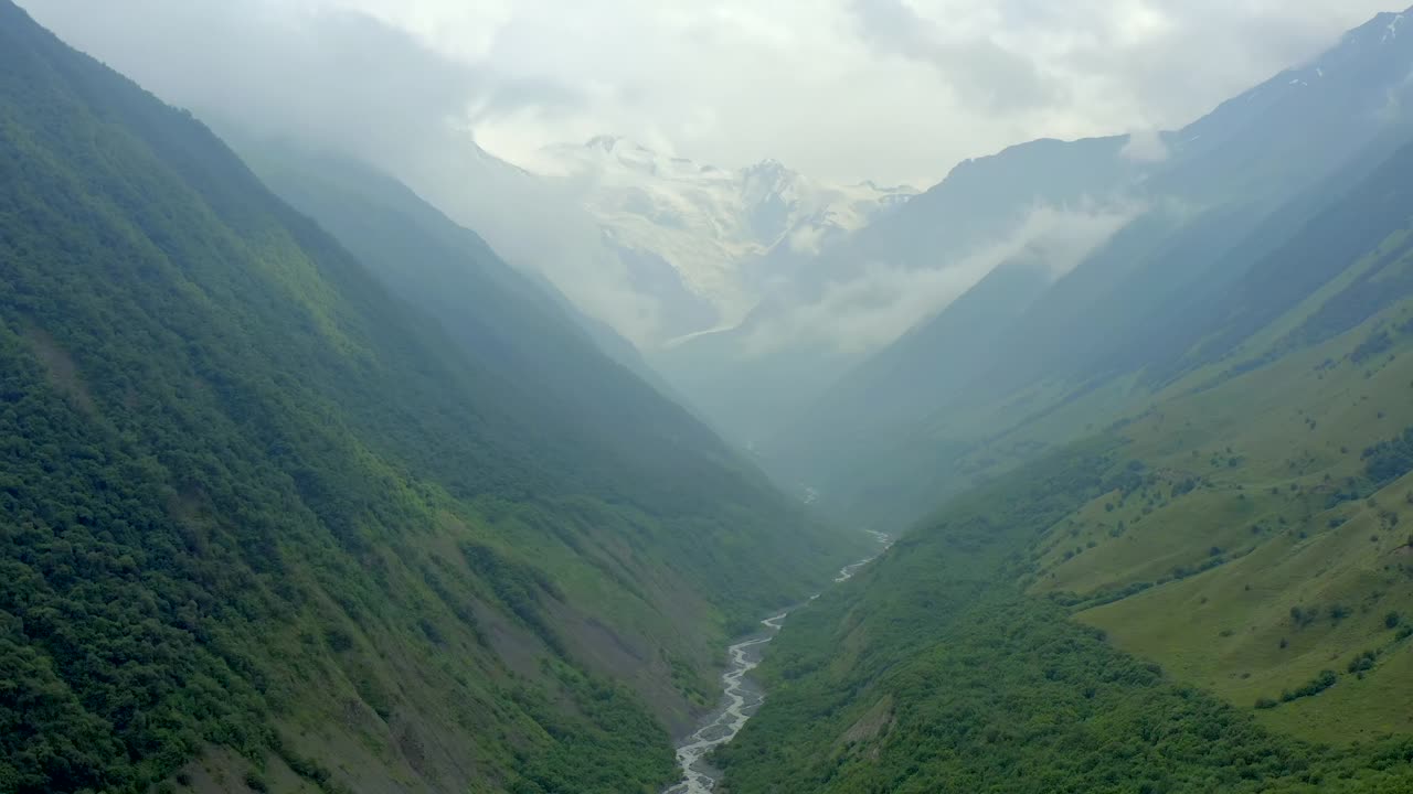 山谷在雾和云。绿草如茵的小山和山间的河流视频素材