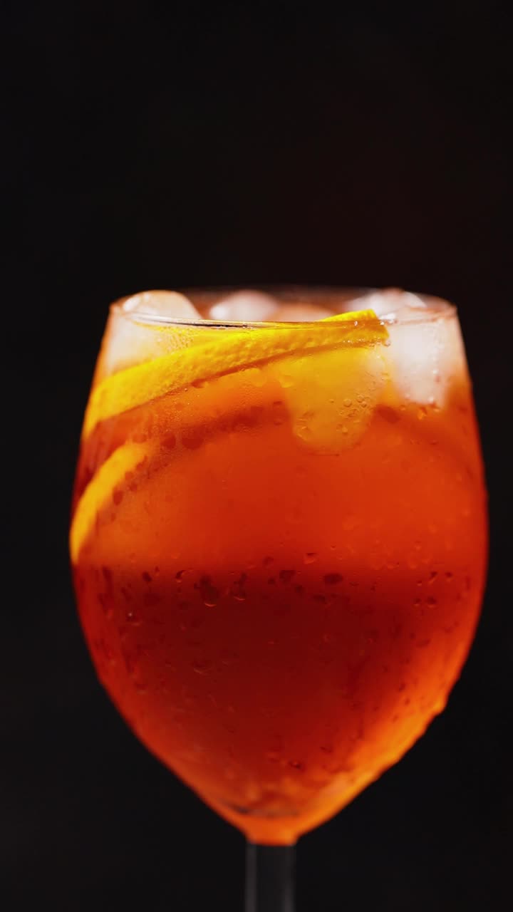 Aperol喷雾鸡尾酒在黑色背景上旋转。夏日橙子鸡尾酒旋转杯。旋转。垂直屏幕方向，9:16视频素材