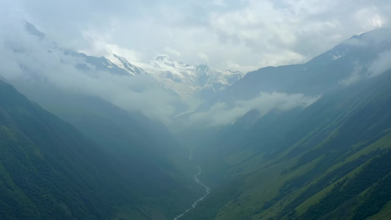 无人机沿着河流在山脉之间下降。山谷视频素材