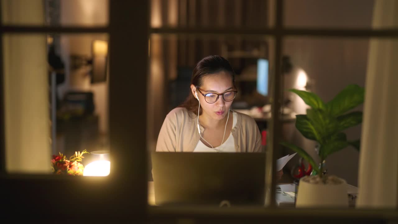 亚洲女商人晚上加班在家用笔记本电脑进行视频电话会议或虚拟会议视频素材