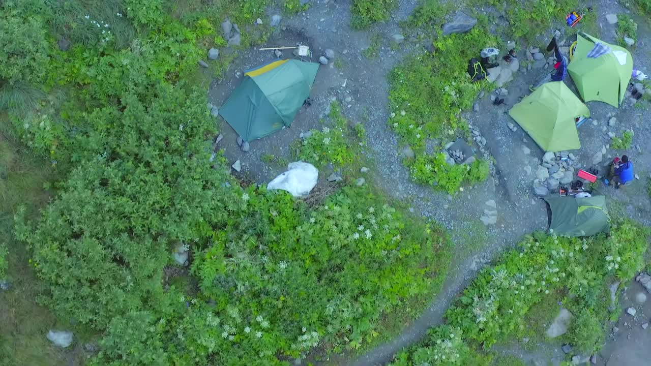 鸟瞰在山麓植物丛中露营的游客帐篷。视频素材