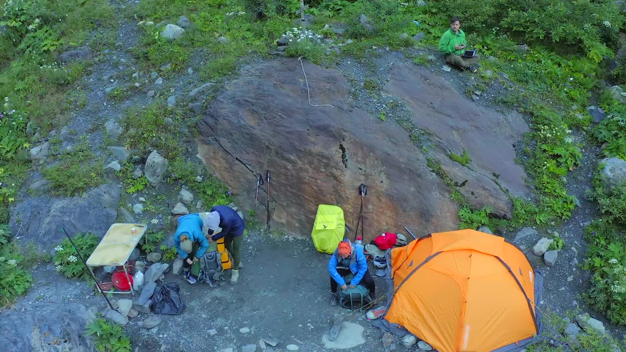 在徒步旅行之前，游客们会在早上收拾好帐篷。在山里露营视频素材