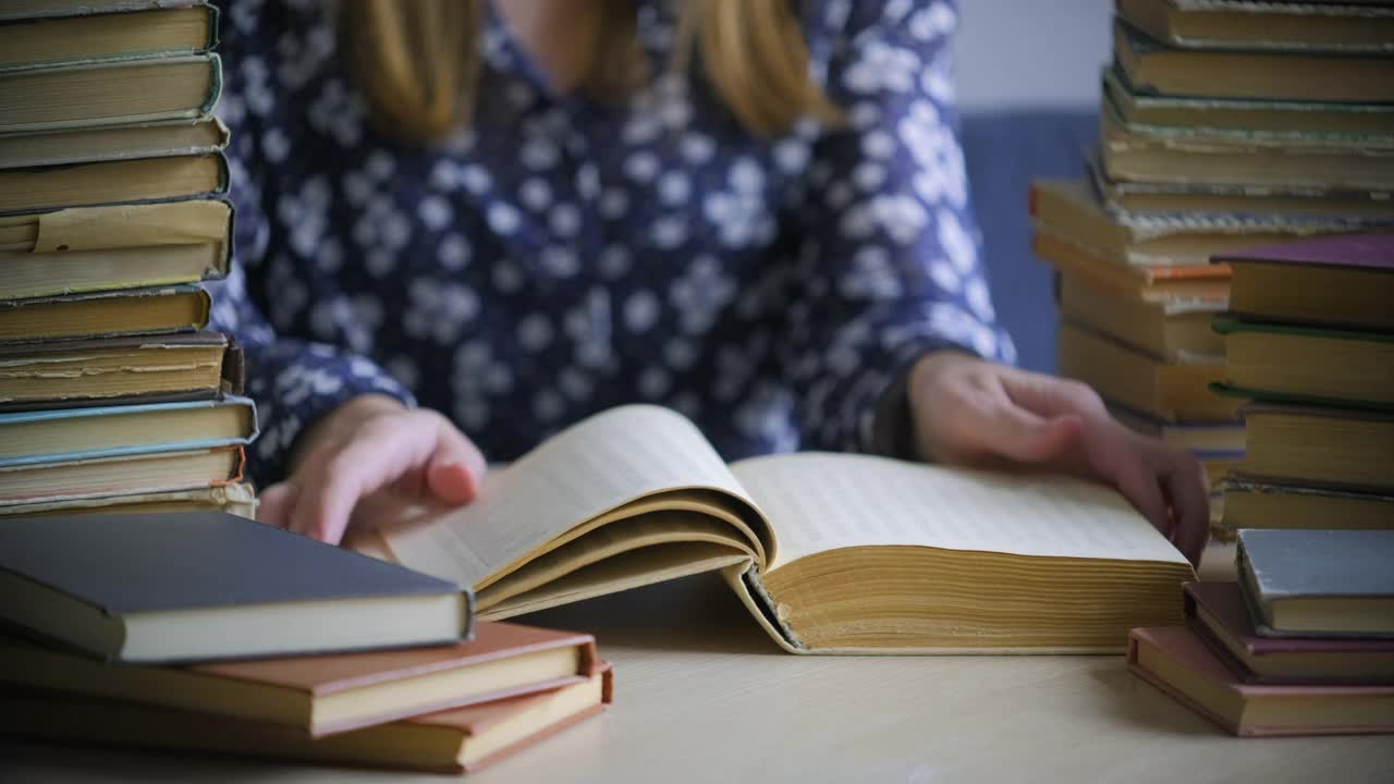 图书馆里有很多书。女人的手翻着旧书的书页。阅读与教育的概念。特写，选择性聚焦视频素材