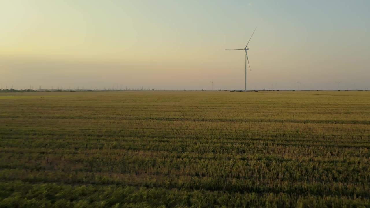 在一个美丽的夏夜，鸟瞰乡间已修剪过的田野上的风车。视频素材