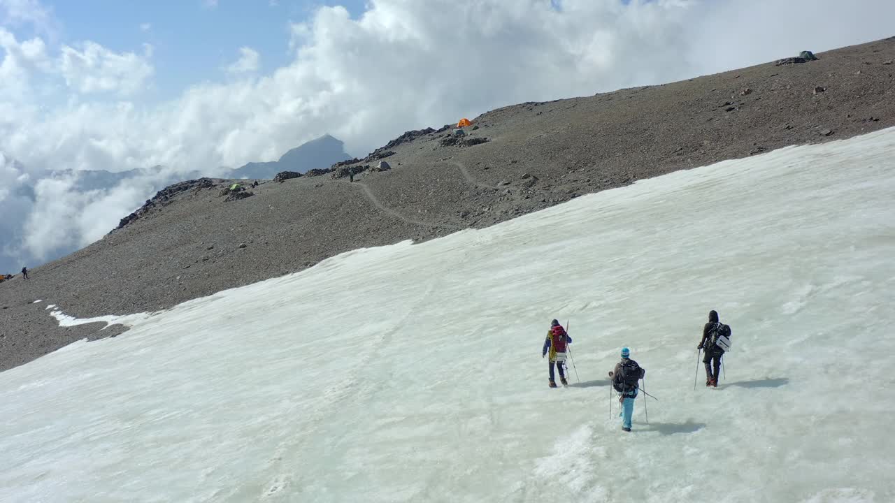 三名登山者在完成艰难的上坡攀登并返回突击营地之前，迈出了穿越冰川的最后一步。视频素材