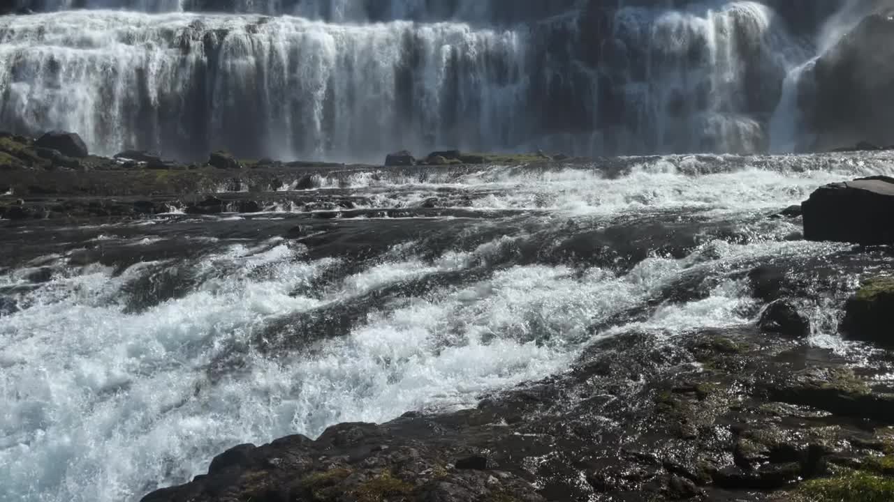 小溪从巨大的瀑布中流出，流经郁郁葱葱的绿色山坡。视频素材