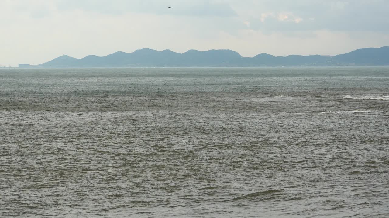 4k波光粼粼的海洋海水海浪表面和海岸岩石海岸云朵云景。视频素材