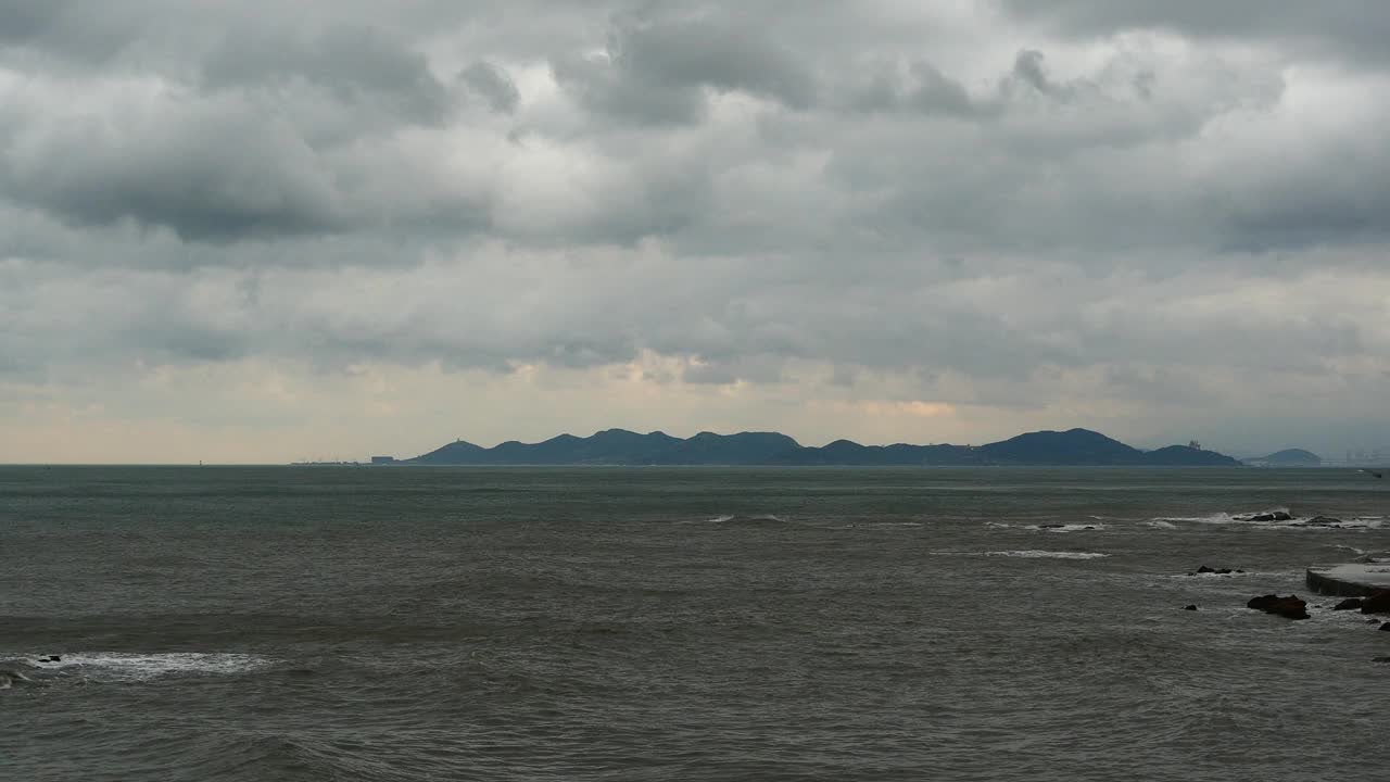 4k波光粼粼的海洋海水海浪表面和海岸岩石海岸云朵云景。视频素材