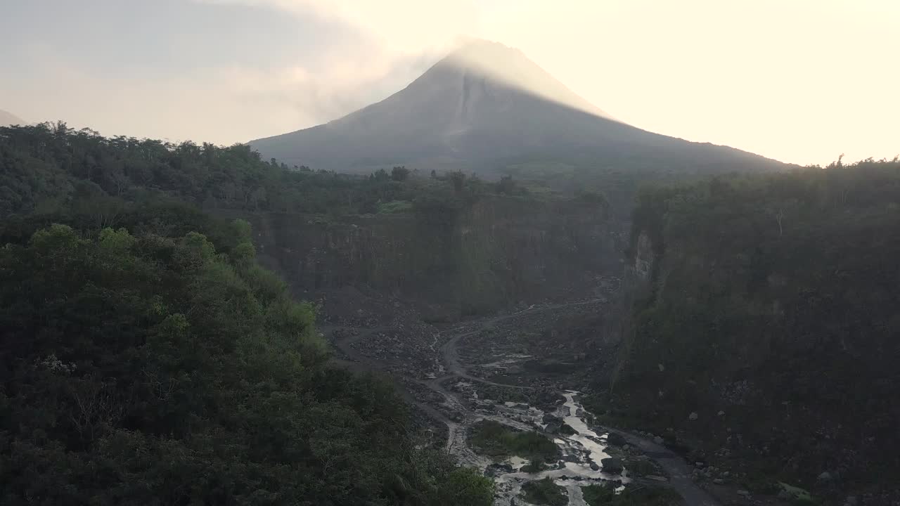 无人机拍摄的湖泊和火山在日出时爆发的自然景观。湖被树木环绕着。你还可以看到从火山喷发出来的物质经过的河流视频素材