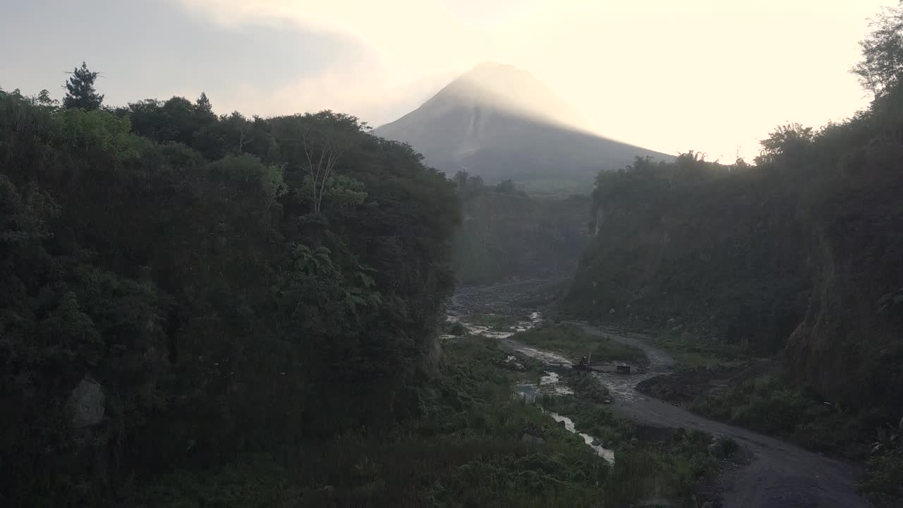 无人机拍摄的湖泊和火山在日出时爆发的自然景观。湖被树木环绕着。你还可以看到从火山喷发出来的物质经过的河流视频素材