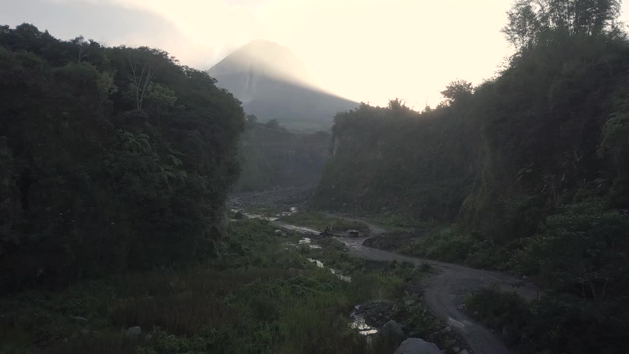 无人机拍摄的湖泊和火山在日出时爆发的自然景观。湖被树木环绕着。你还可以看到从火山喷发出来的物质经过的河流视频素材