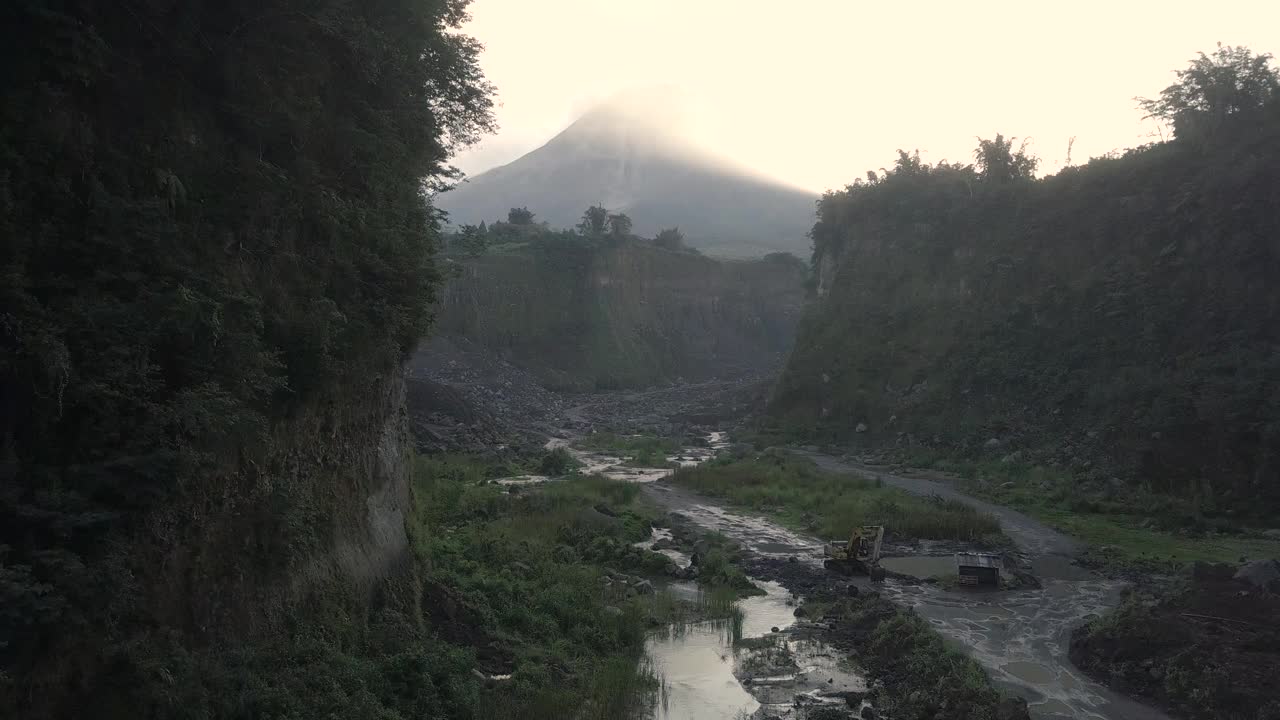 无人机拍摄的湖泊和火山在日出时爆发的自然景观。湖被树木环绕着。你还可以看到从火山喷发出来的物质经过的河流视频素材