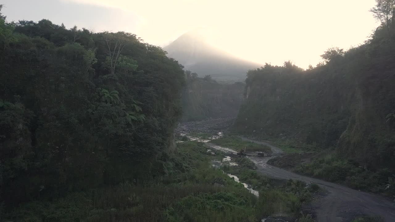 无人机拍摄的湖泊和火山在日出时爆发的自然景观。湖被树木环绕着。你还可以看到从火山喷发出来的物质经过的河流视频素材