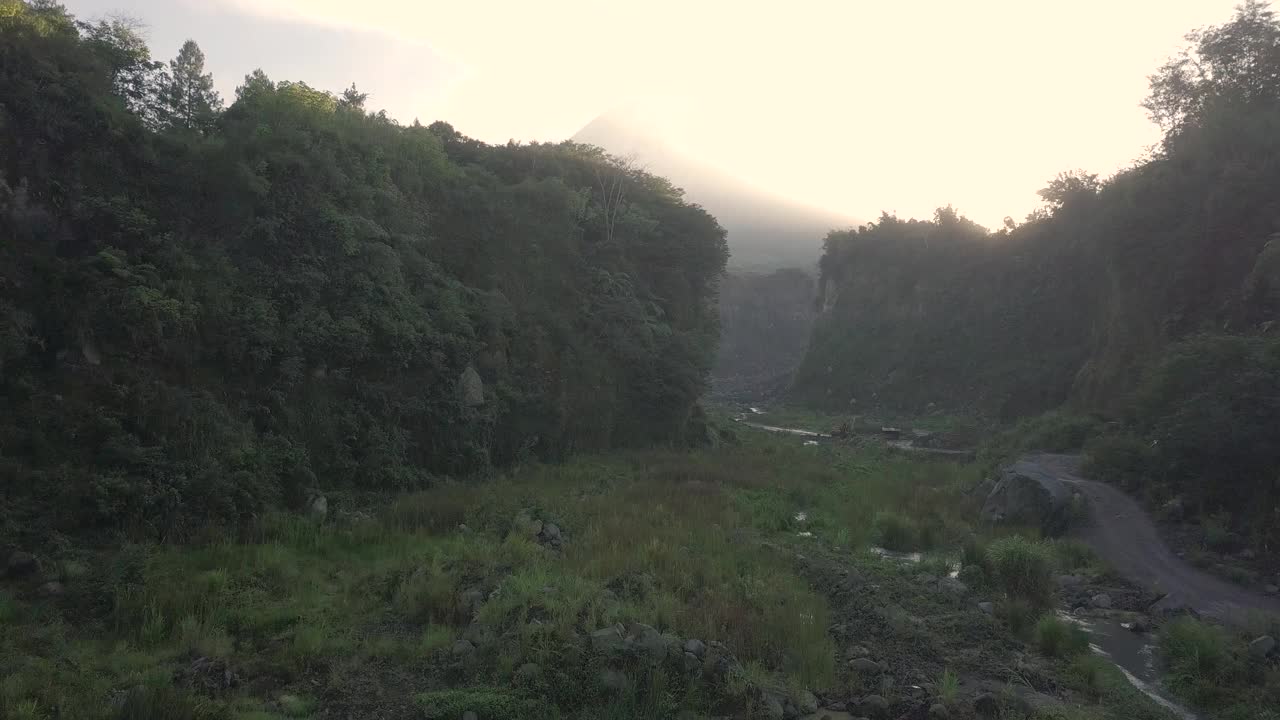 无人机拍摄的湖泊和火山在日出时爆发的自然景观。湖被树木环绕着。你还可以看到从火山喷发出来的物质经过的河流视频素材