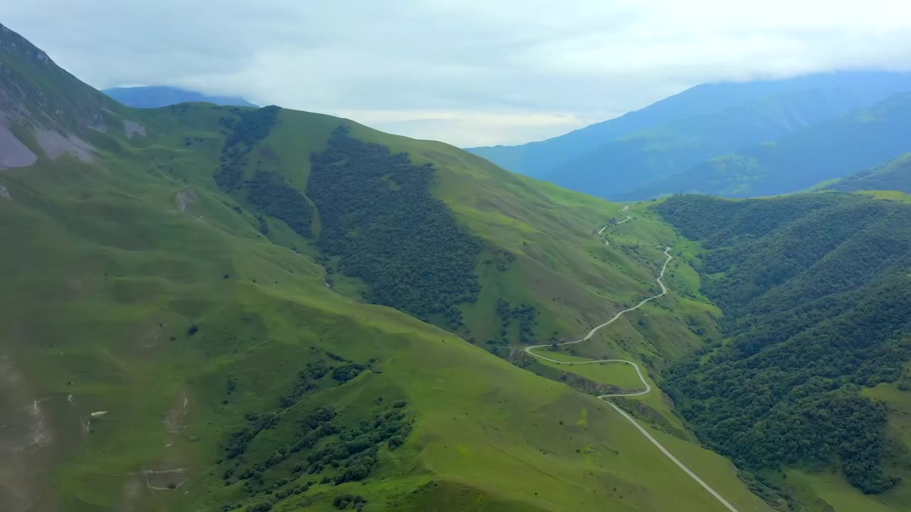 鸟瞰图，一条蜿蜒的道路在山上的绿色草地。视频素材