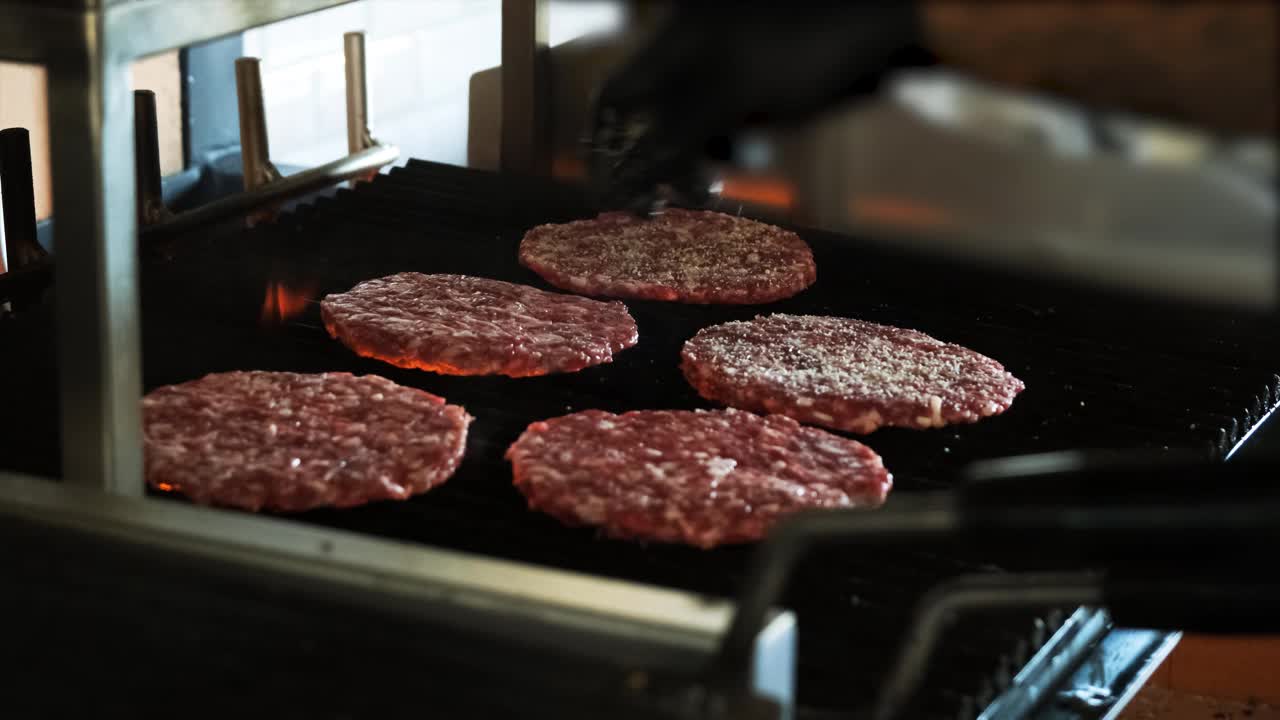 烤肉架上用来做汉堡的美味肉。火是燃烧。酋长在汉堡上撒盐。视频下载