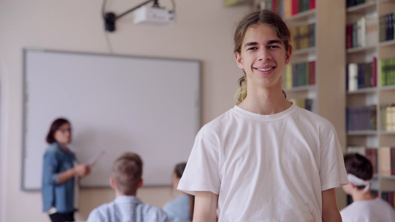 微笑自信的男学生少年在图书馆看着相机的肖像视频素材