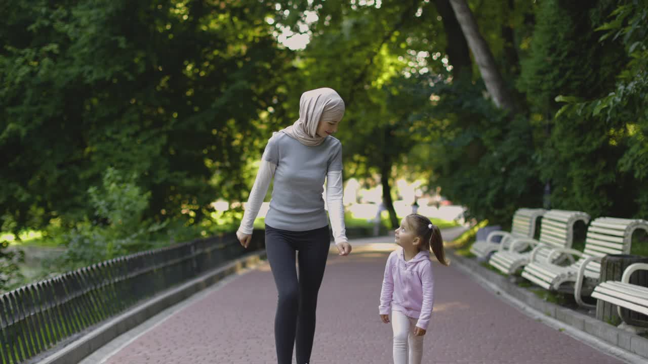 一位穆斯林阿拉伯妇女和她活泼可爱的4岁女儿在公园里一起跑步视频素材